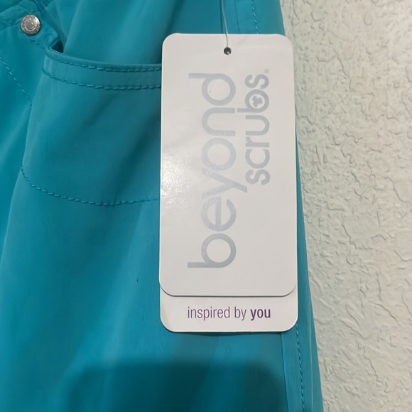 Teal scrubs with five pockets. One is a zip pocket. - Picture 3 of 4